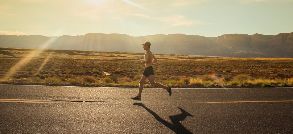 Фотография: спортсмен бежит по асфальтированной дороге на фоне бескрайнего поля и палящего солнца