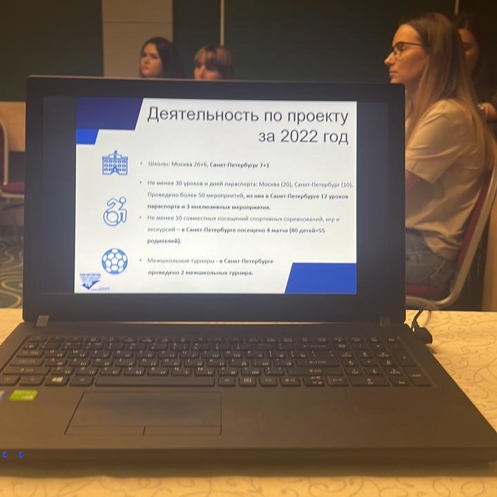 На переднем плане ноутбук, на экране которого "Деятельность по проекту за 2022 год", на заднем плане сидят участники семинара