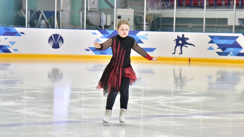 Девочка с ментальными особенностями на фигурных коньках на ледовой площадке