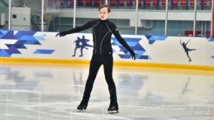 Молодой человек с ментальными особенностями на фигурных коньках на ледовой площадке