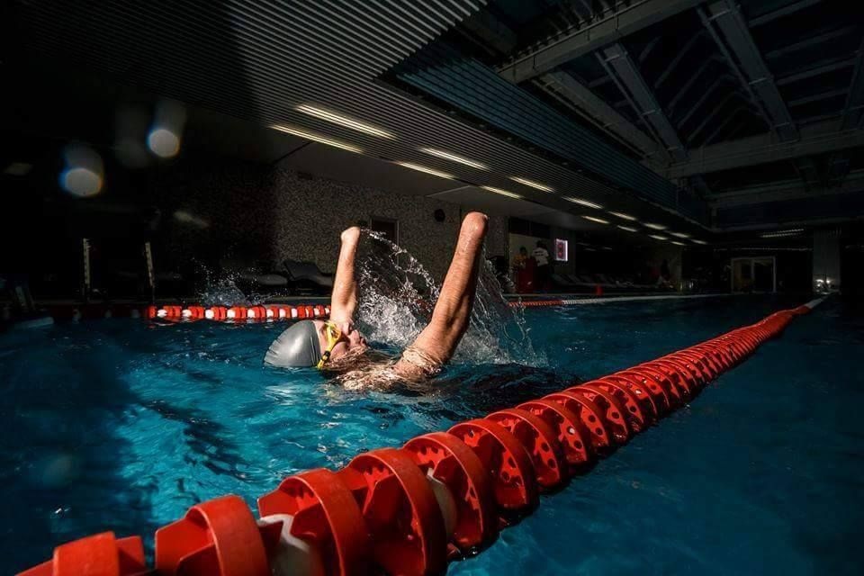Мужчина с ампутированными кистями рук плывёт на спине в бассейне по спортивной дорожке (фотография со стены Евгения Машковского ВКонтакте)