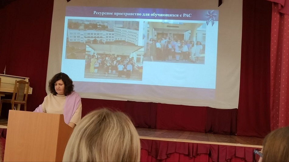 учитель ресурсного пространства для детей с РАС Евгения Исмайлова с кафедры читает лекцию на фоне презентации