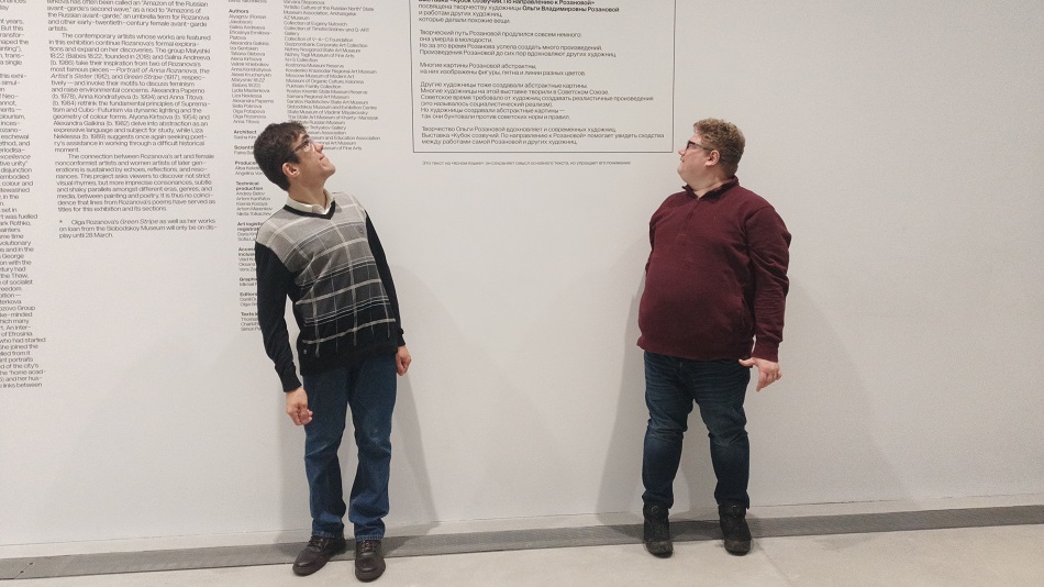 2 участника программ фонда у стены с текстами взирают на плоды своего труда в экспозиции выставки ГЭС-2