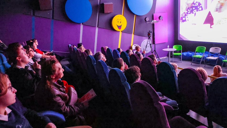 Зрители и фрагмент киноэкрана в кинозале во время просмотра фильма кинофестиваля "Кино без барьеров"